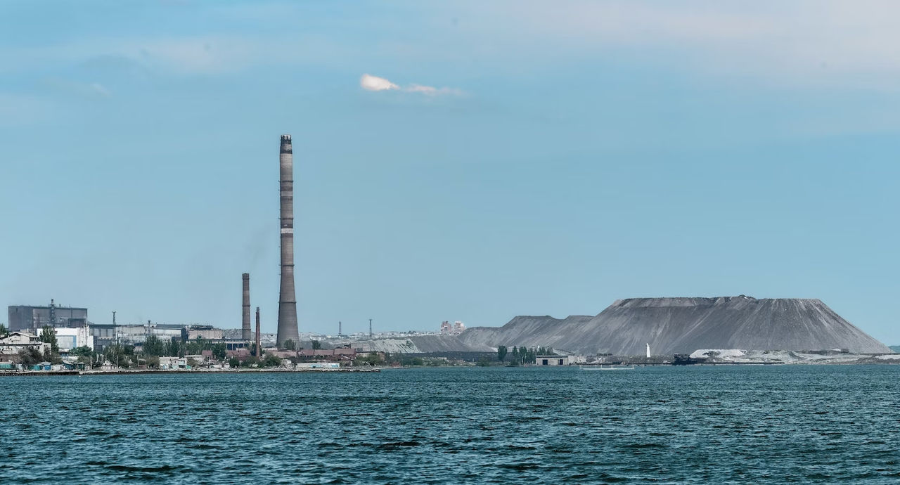 Oil refinery on the shore of a large body of water.