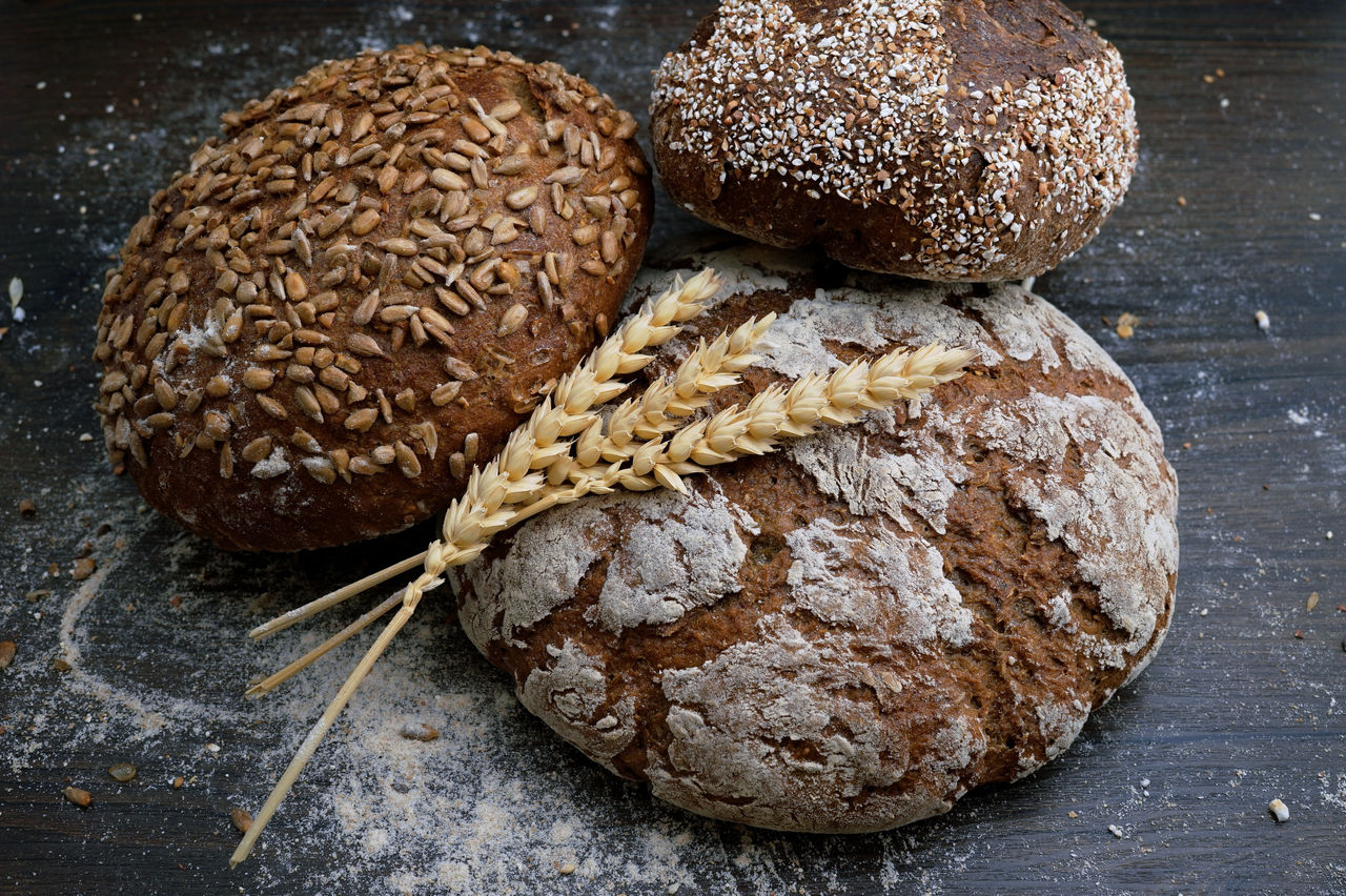 Tres panes redondos con semillas y pedazos de trigo encima.