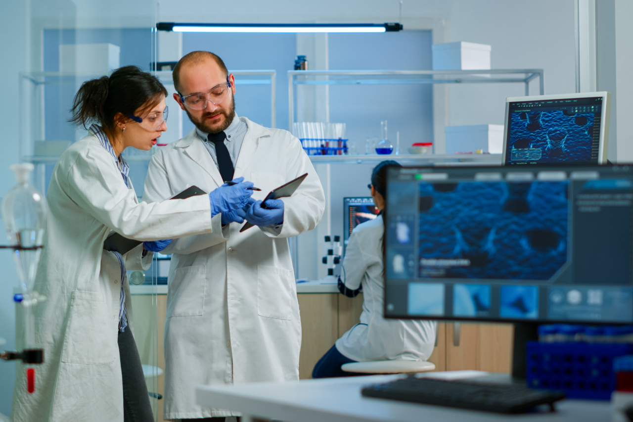Laboratoire moderne de recherche médicale : Deux scientifiques travaillent, utilisent une tablette numérique, analysent des résultats et discutent. Laboratoire pharmaceutique scientifique de pointe consacré à la médecine et au développement biotechnologique.